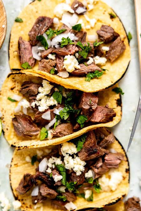 Steak tacos with cilantro, onion, and cheese